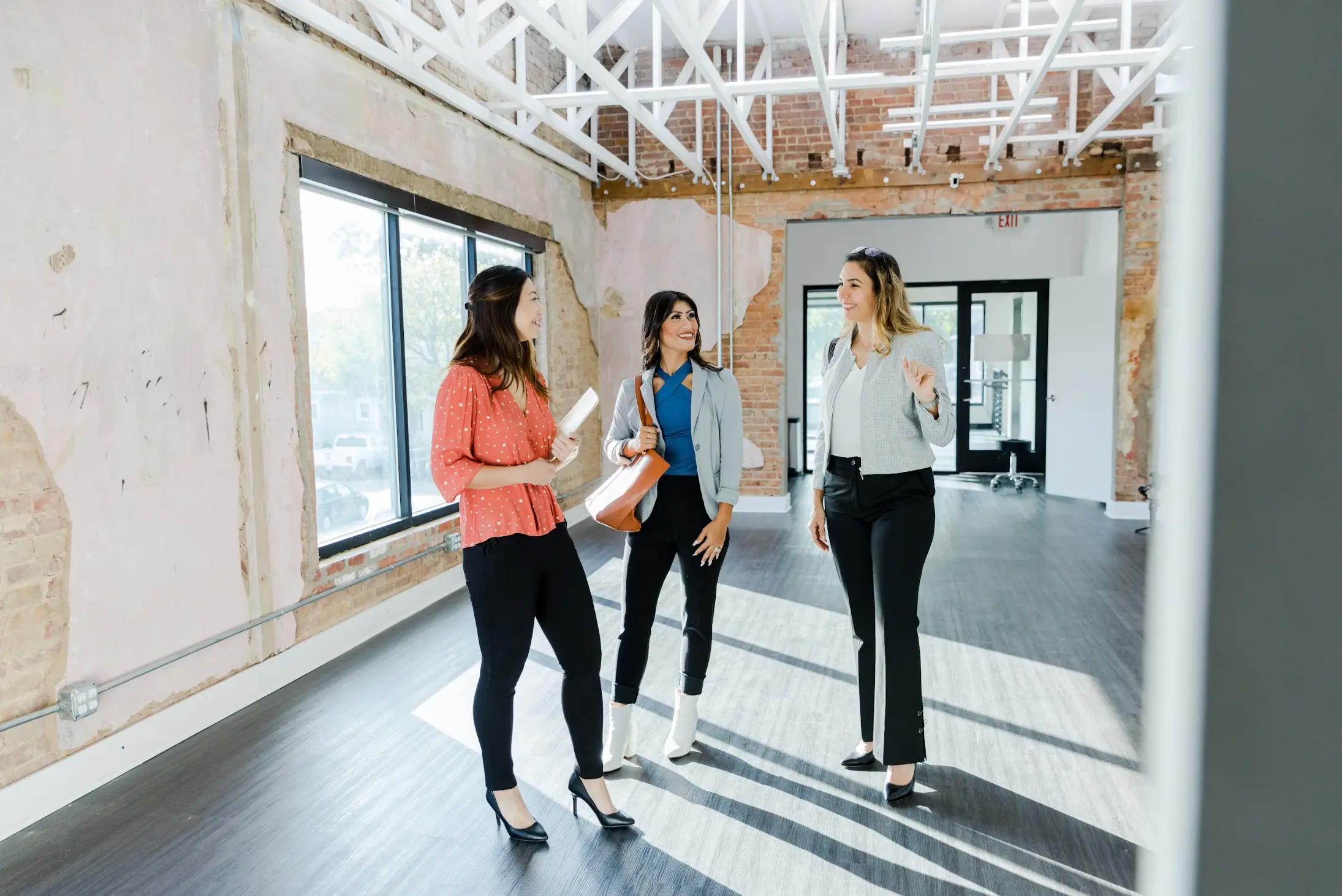 Real estate professionals touring a loft-style commercial property with exposed brick and modern flooring.