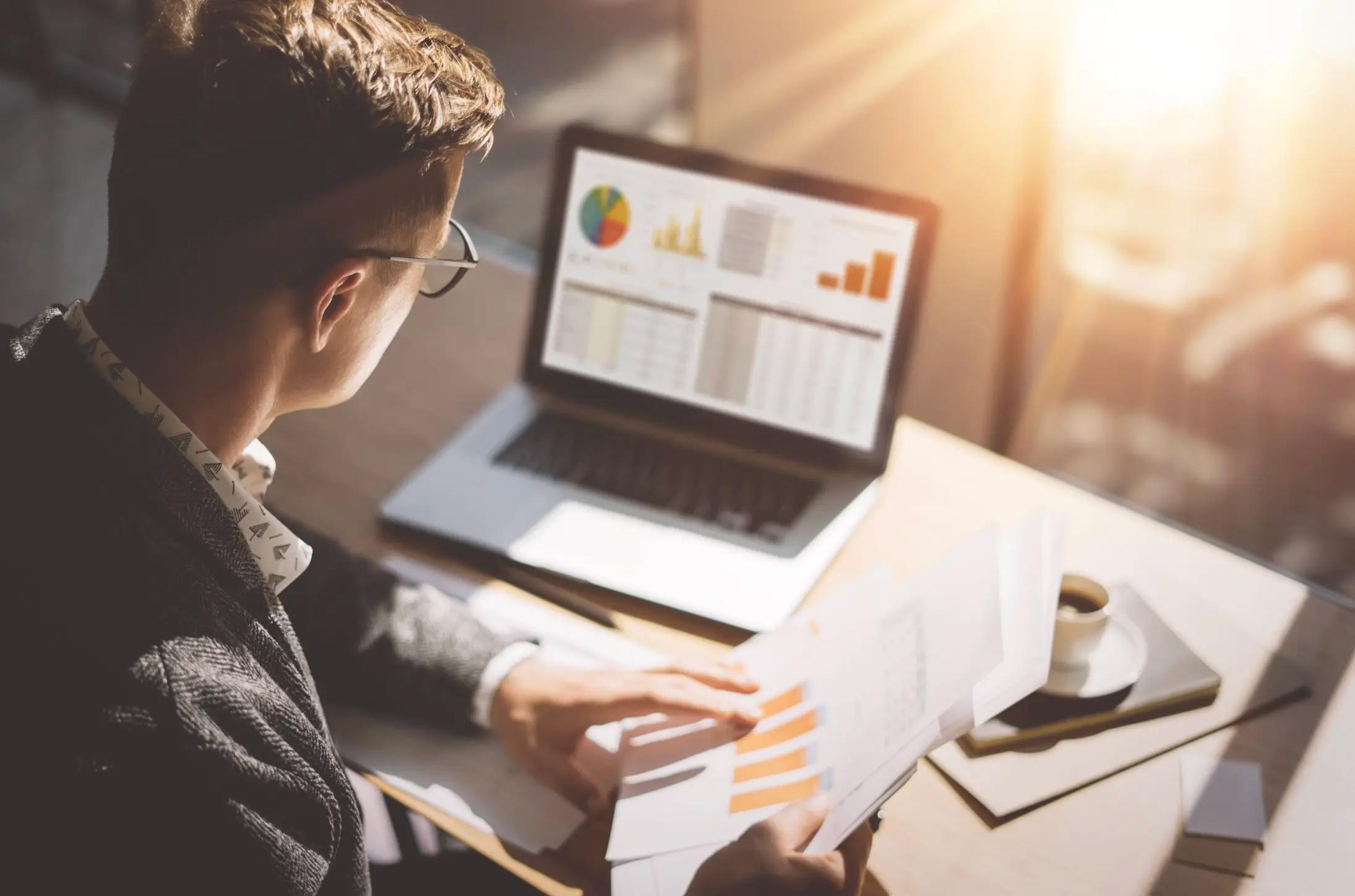 Professional reviewing investment data and performance charts in a bright modern workspace.