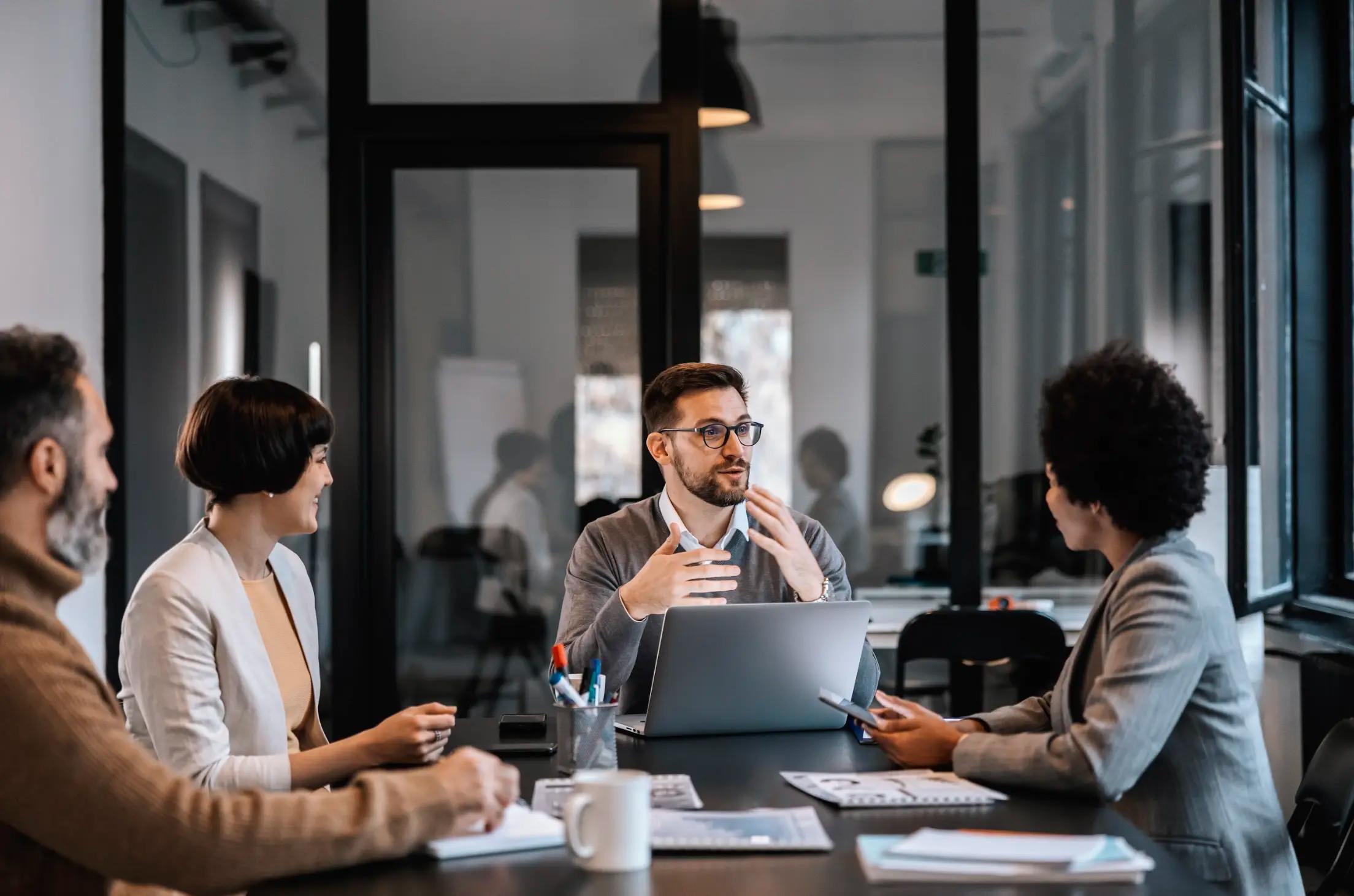 Group of professionals having a discussion around a conference table in a modern office.